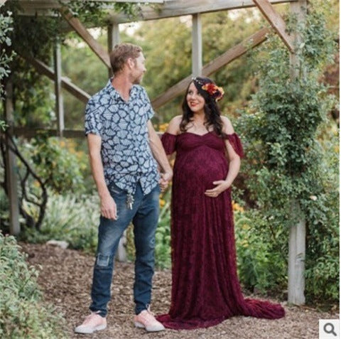 Maternity Korean-style lace dress in maroon, featuring an off-shoulder design, worn by a pregnant woman standing outdoors with a partner.