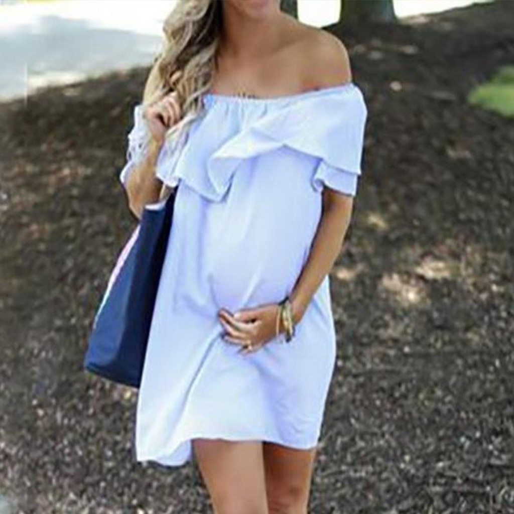 Maternity dress with shoulder flounce, outdoor setting.