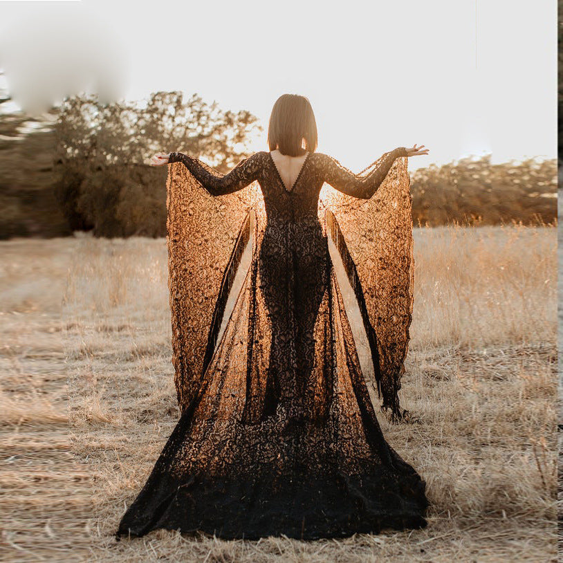 Maternity lace drawstring dress with sheer black lace, long sleeves, and elegant flowing design in a scenic outdoor setting.